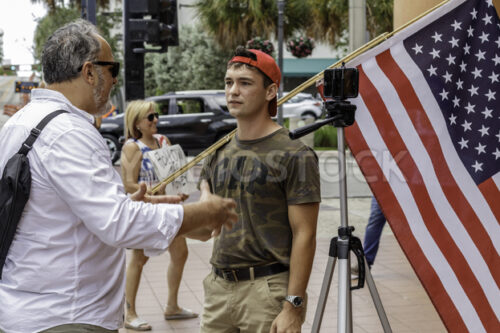 News media interviewing a male protester with American flag